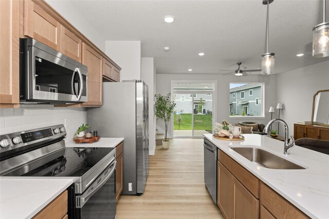 234 NW Waverly Dr, Waukee, IA 50263 - kitchen featuring stainless steel appliances, a sink, light wood-type flooring, open floor plan, and tasteful backsplash