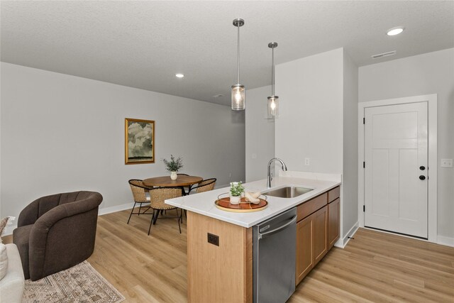 234 NW Waverly Dr, Waukee, IA 50263 - kitchen featuring stainless steel dishwasher, a sink, light wood-style floors, open floor plan, and decorative light fixtures