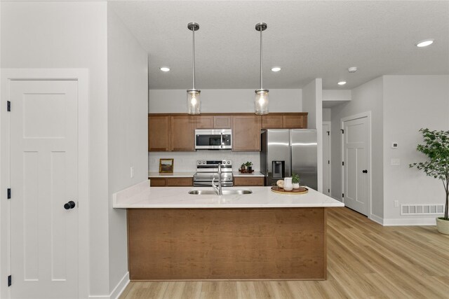 234 NW Waverly Dr, Waukee, IA 50263 - kitchen with appliances with stainless steel finishes, a sink, tasteful backsplash, brown cabinetry, and light wood-style floors