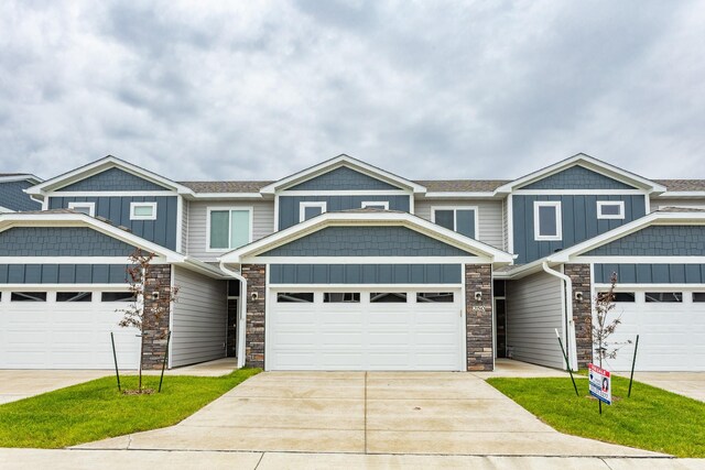 234 NW Waverly Dr, Waukee, IA 50263 - view of front of home with stone siding, driveway, board and batten siding, and an attached garage