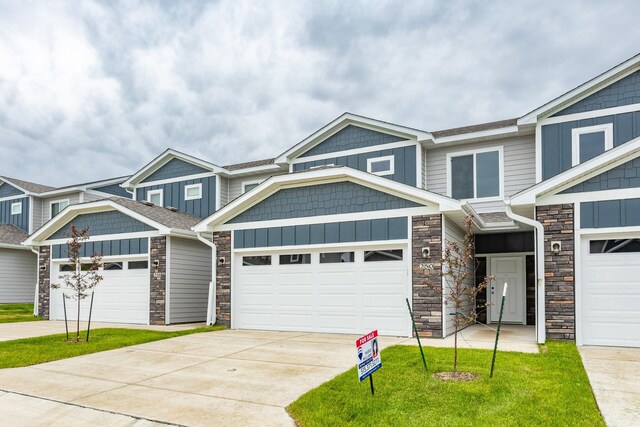 234 NW Waverly Dr, Waukee, IA 50263 - view of front of house featuring stone siding, driveway, an attached garage, and board and batten siding