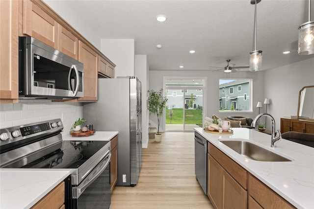 230 NW Waverly Dr, Waukee, IA 50263 - kitchen featuring stainless steel appliances, a sink, light wood-type flooring, open floor plan, and tasteful backsplash