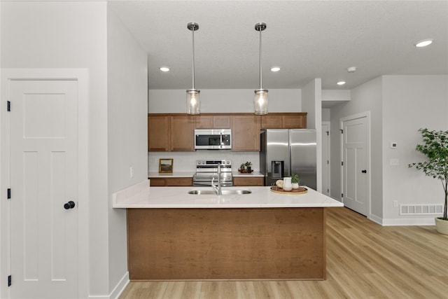 230 NW Waverly Dr, Waukee, IA 50263 - kitchen with appliances with stainless steel finishes, a sink, tasteful backsplash, brown cabinetry, and light wood-style floors