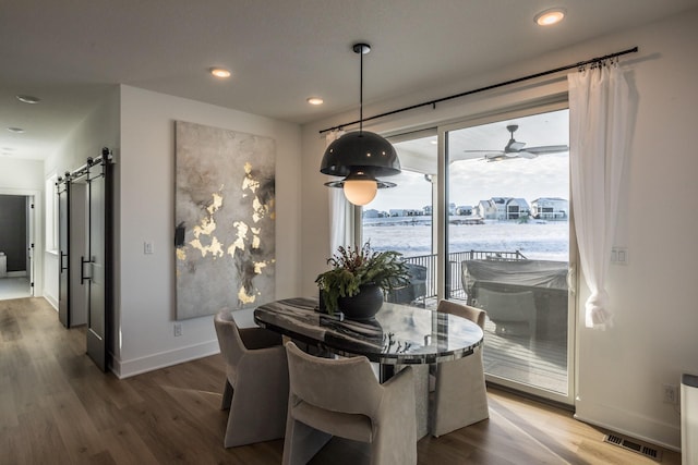 dining room with hardwood / wood-style floors, ceiling fan, and a barn door