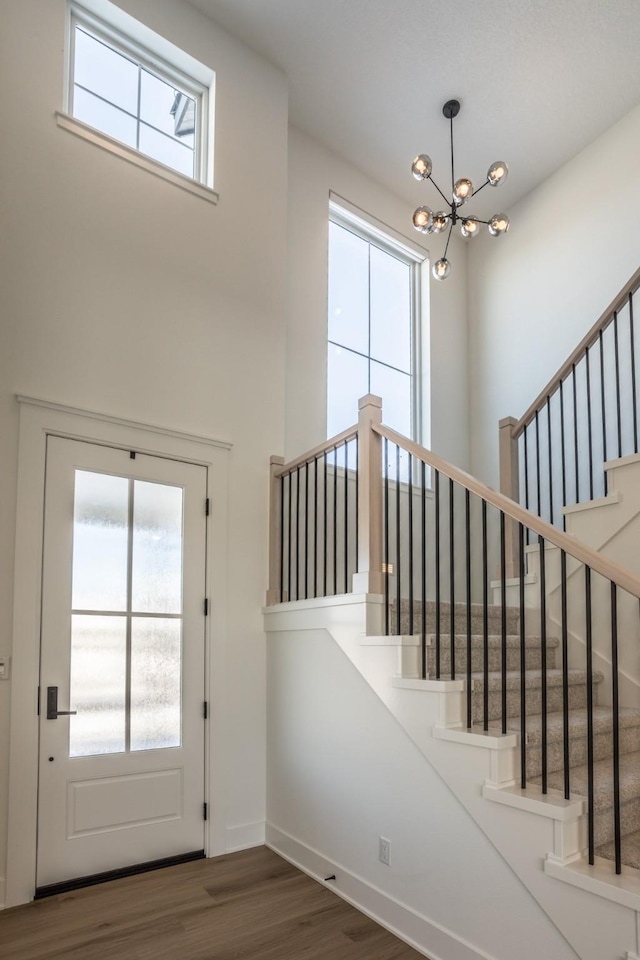 interior space with dark hardwood / wood-style flooring, a towering ceiling, and an inviting chandelier