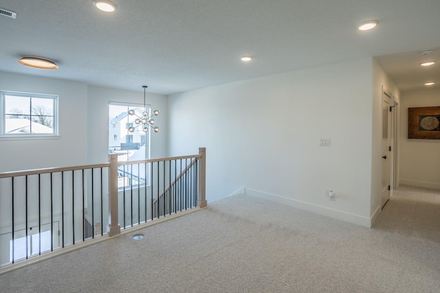 unfurnished room with carpet floors and a chandelier