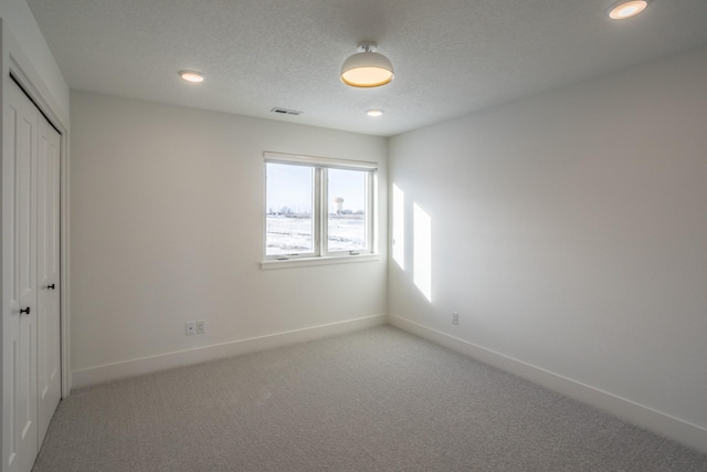 unfurnished bedroom with carpet floors, a textured ceiling, and a closet