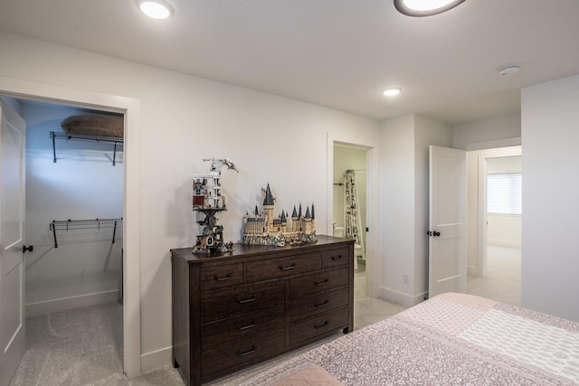 bedroom featuring light colored carpet, a spacious closet, and a closet