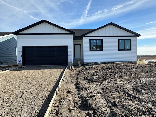 ranch-style home featuring a garage and gravel driveway