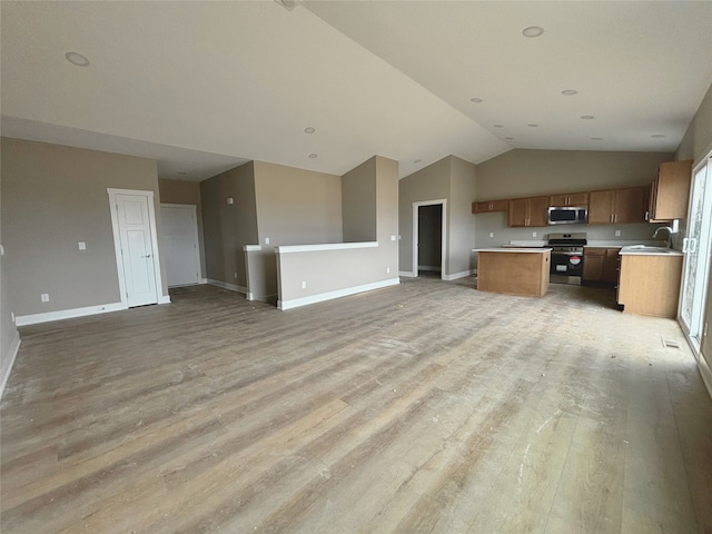 kitchen featuring brown cabinets, stainless steel appliances, light countertops, light wood-style floors, and open floor plan