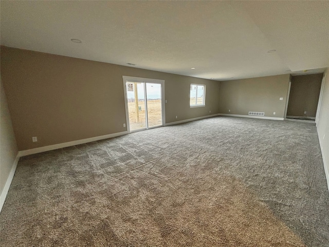 empty room with carpet flooring, visible vents, and baseboards