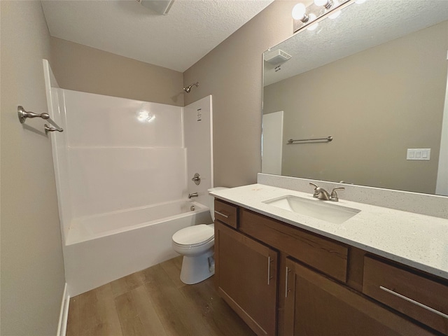 bathroom with shower / washtub combination, toilet, vanity, a textured ceiling, and wood finished floors