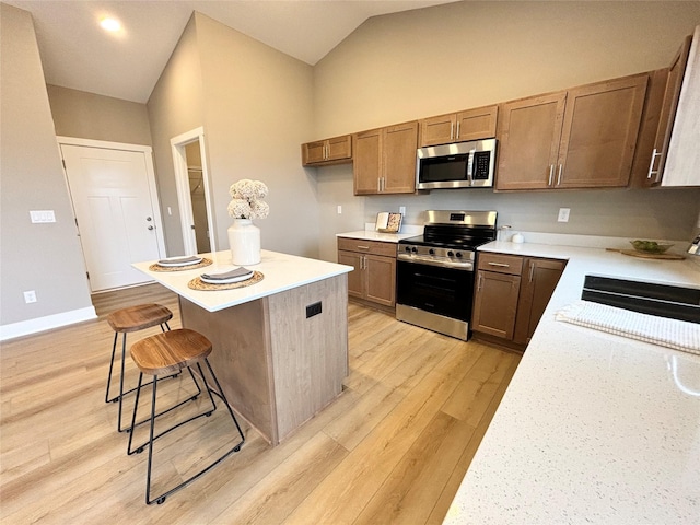 1677 20th Ave SE, Altoona, IA 50009 - kitchen featuring stainless steel appliances, light wood-style floors, a breakfast bar area, a center island, and vaulted ceiling