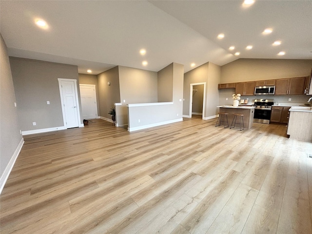 1677 20th Ave SE, Altoona, IA 50009 - kitchen with appliances with stainless steel finishes, open floor plan, light countertops, baseboards, and vaulted ceiling
