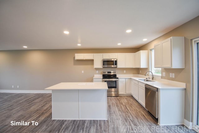 kitchen with hardwood / wood-style floors, a center island, white cabinets, sink, and appliances with stainless steel finishes