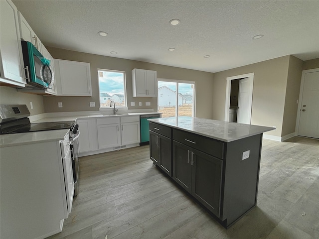 kitchen featuring white cabinets, a center island, stainless steel appliances, dark cabinetry, and light countertops