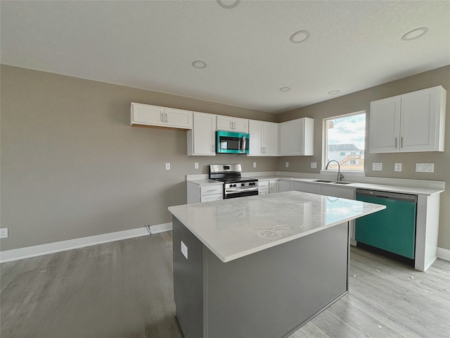 kitchen featuring stainless steel appliances, a center island, white cabinetry, and a sink