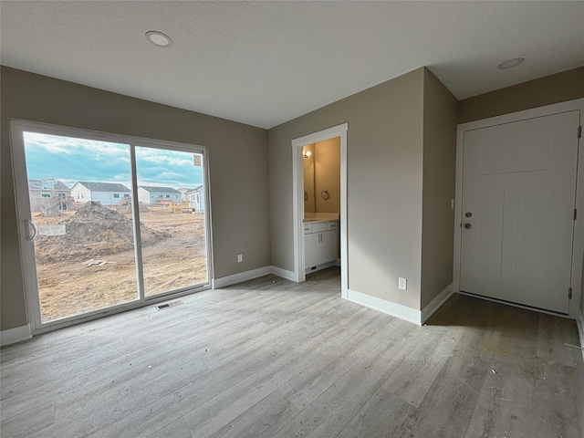 unfurnished bedroom with access to exterior, visible vents, ensuite bathroom, light wood-style floors, and baseboards