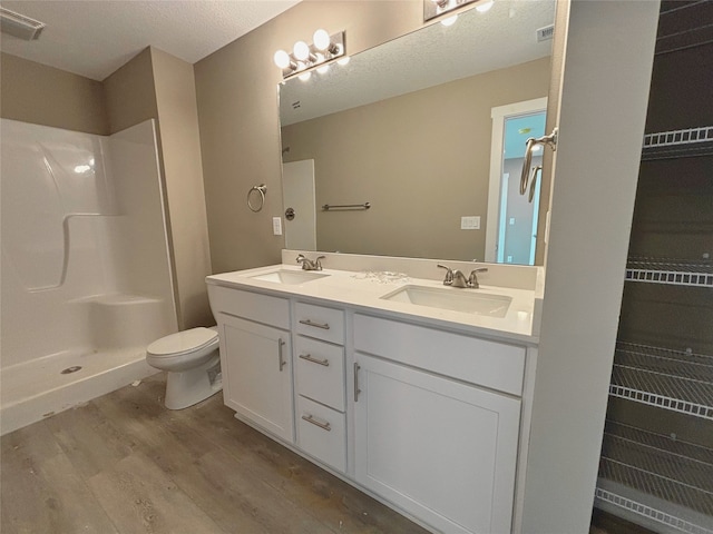 bathroom featuring toilet, double vanity, a sink, and wood finished floors