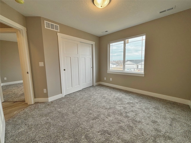 unfurnished bedroom featuring carpet floors, visible vents, and a closet