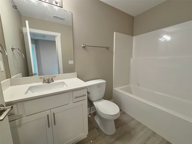 bathroom featuring visible vents, toilet, washtub / shower combination, vanity, and wood finished floors