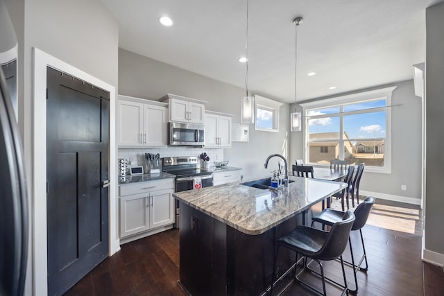 kitchen with pendant lighting, white cabinetry, sink, and appliances with stainless steel finishes