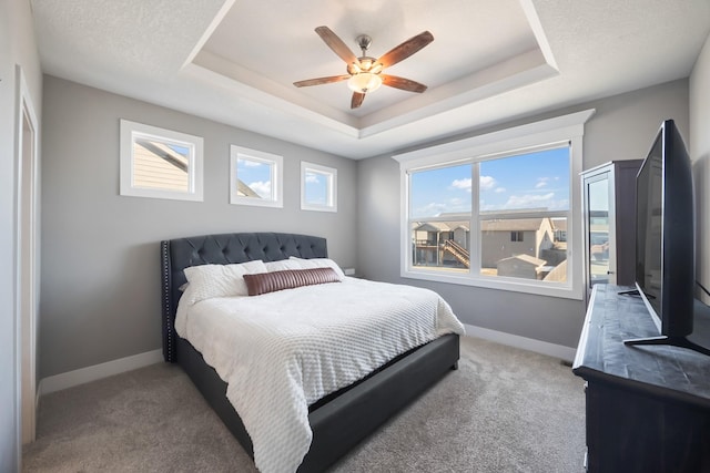 bedroom with ceiling fan, a raised ceiling, and light colored carpet