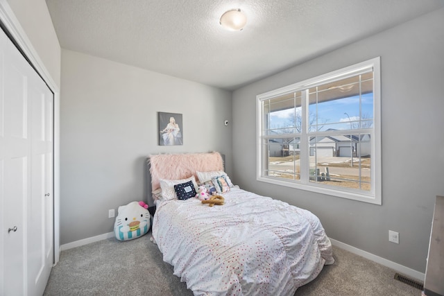 carpeted bedroom featuring a textured ceiling and a closet