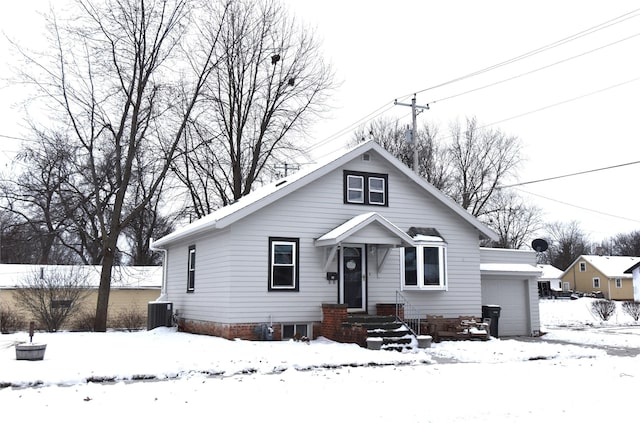 bungalow-style house with central AC unit and a garage