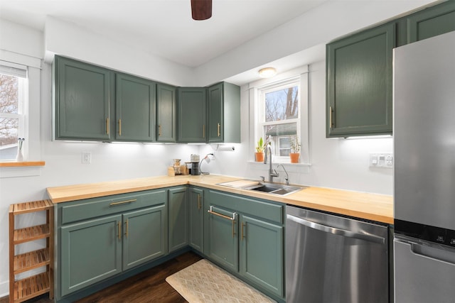 kitchen featuring butcher block counters, sink, stainless steel appliances, dark wood-type flooring, and green cabinets