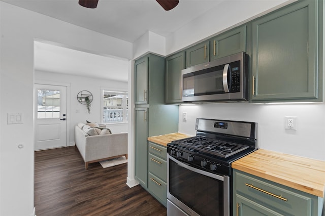 kitchen with appliances with stainless steel finishes, dark wood-type flooring, wooden counters, and green cabinetry