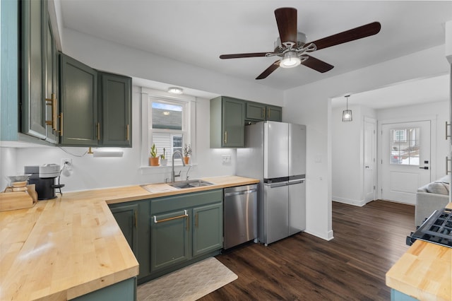 kitchen with wood counters, appliances with stainless steel finishes, sink, and green cabinets