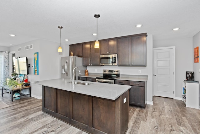 kitchen featuring dark brown cabinets, sink, decorative light fixtures, and appliances with stainless steel finishes