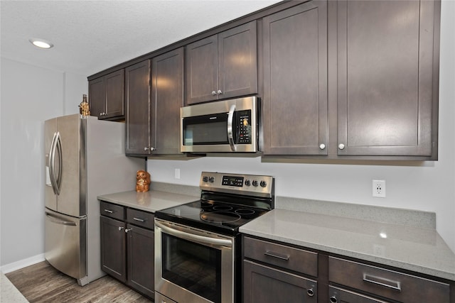 kitchen featuring appliances with stainless steel finishes, dark brown cabinetry, and light stone counters