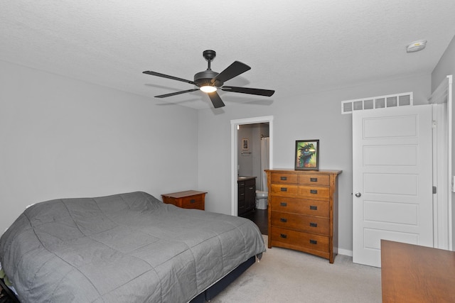 carpeted bedroom with ceiling fan, ensuite bathroom, and a textured ceiling