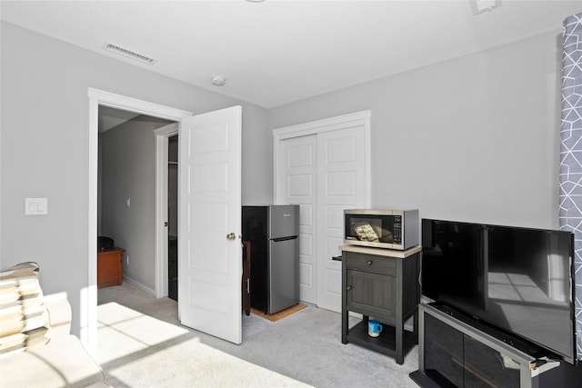 carpeted bedroom featuring stainless steel fridge and a closet