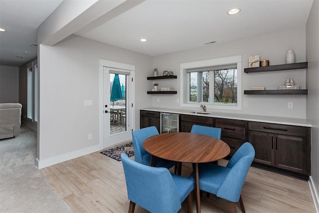 kitchen with sink, dark brown cabinets, light hardwood / wood-style floors, and beverage cooler