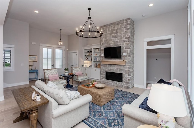 living room with a notable chandelier, plenty of natural light, light hardwood / wood-style floors, and a fireplace