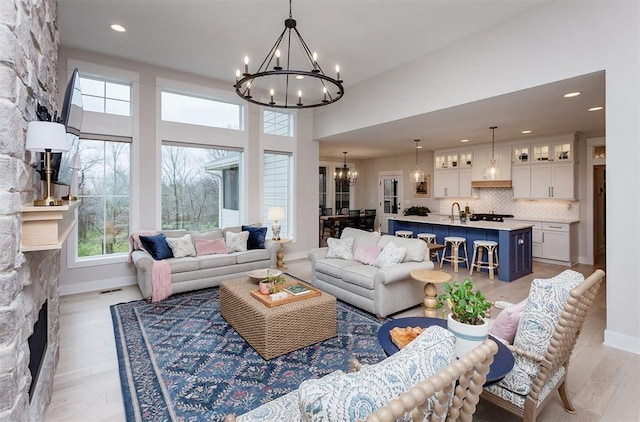 living room with light wood-type flooring, a fireplace, and a chandelier