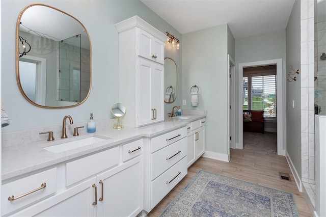 bathroom with hardwood / wood-style flooring, vanity, and a shower