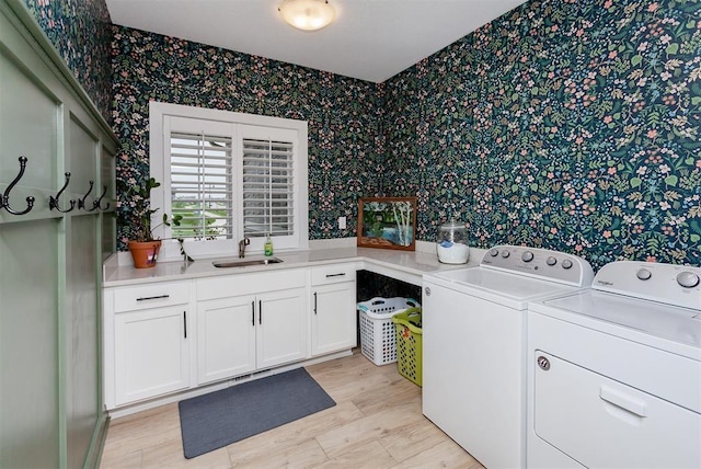 laundry room with cabinets, washer and clothes dryer, sink, and light wood-type flooring