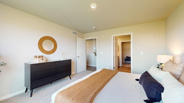 bedroom featuring visible vents, light carpet, and baseboards