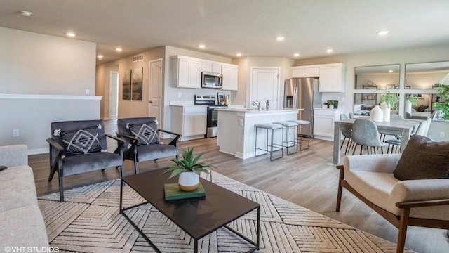 living room featuring light wood-style floors, recessed lighting, and visible vents