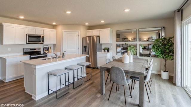 kitchen featuring light wood-type flooring, a center island with sink, white cabinetry, and stainless steel appliances