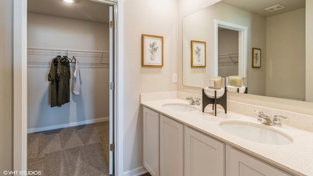 bathroom with visible vents, a sink, a spacious closet, and double vanity