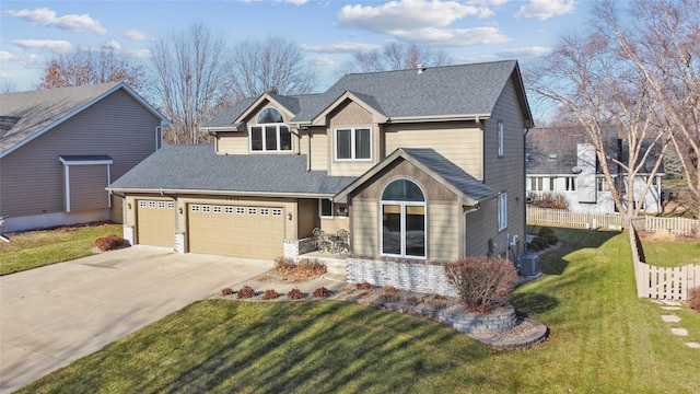 view of front facade with a shingled roof, concrete driveway, an attached garage, fence, and a front yard