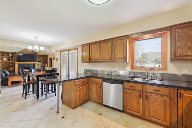 kitchen featuring dishwasher, a peninsula, brown cabinets, and a sink