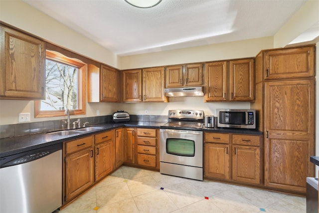 kitchen featuring light tile patterned floors, a textured ceiling, stainless steel appliances, and sink