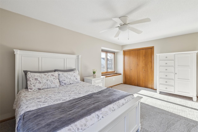 bedroom with a closet, light carpet, baseboards, and a ceiling fan