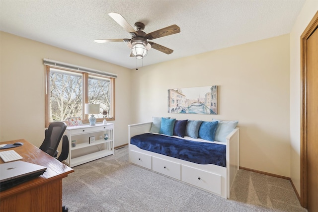 carpeted bedroom with a textured ceiling, baseboards, and a ceiling fan